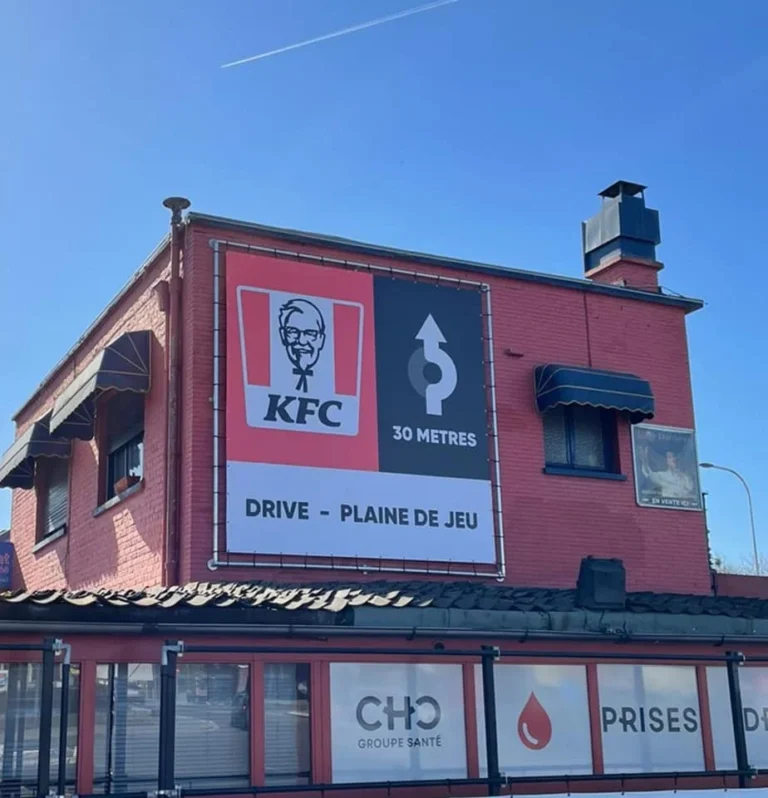Bâche grand format KFC posée en façade d'un bâtiment à Liège, réalisée et posée par Kimva