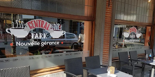Vitrine du café Central Park, nom et « Nouvelle gérance » en lettrage blanc et rouge