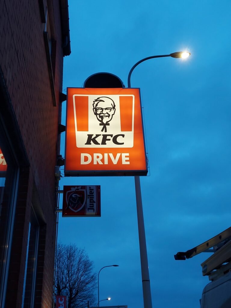 Enseigne lumineuse « KFC Drive », allumée à la tombée du jour